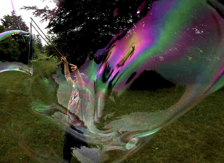 Artist Chris Maher, of Lambertville, Mich., makes bubbles near his booth during the Crosby Festival of the Arts Preview Party at the Toledo Botanical Garden. He says he does this when he gets time between people checking out his art.   (Kurt Steiss / The Blade)